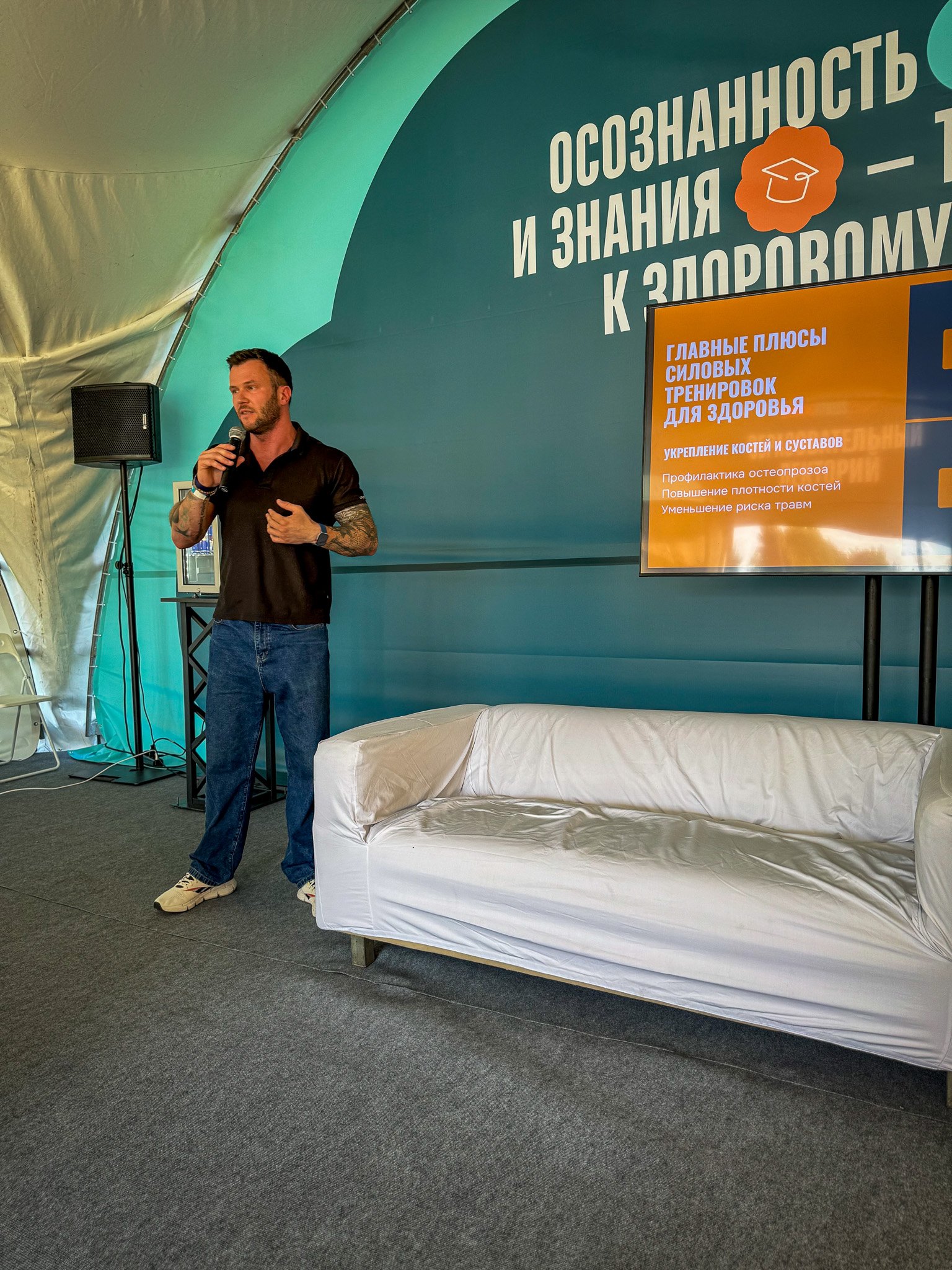 Валентин Барко выступает с микрофоном на семинаре о силовых тренировках и здоровье